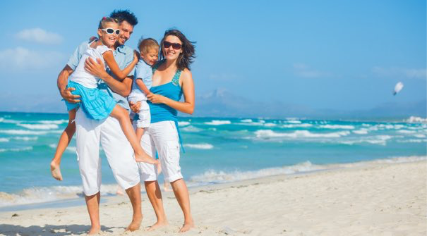 Familia feliz disfrutando un dia de playa, vestida de azul